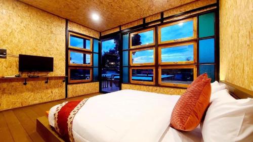 a bedroom with a bed and a tv and windows at Heaven Hill Camping in Ban Thung Na