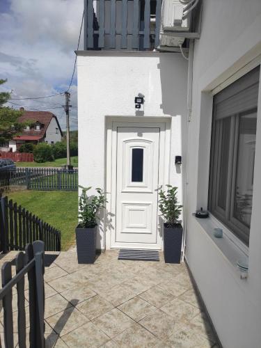 a white door on a white house with potted plants at Sunny Beach in Zánka