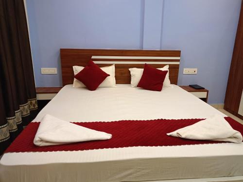 a bed with red and white pillows on it at Sea Wander Beach Resort in Mandarmoni