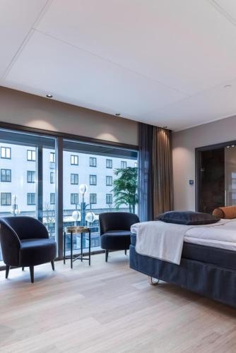 a bedroom with a bed and chairs and a large window at Solo Sokos Hotel Lahden Seurahuone in Lahti
