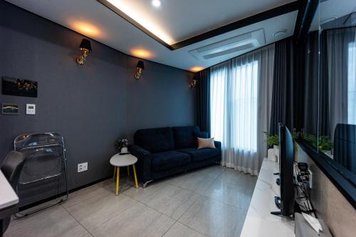 a living room with a blue couch and a tv at 1 minute to the beach! Free parking! Sauna and gym in Busan