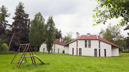 une vieille maison avec une aire de jeux devant elle dans l'établissement Les Gîtes du Bois de Chelles, à La Chapelle-Geneste