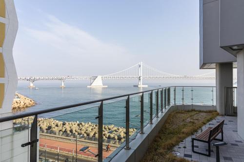 a balcony with a view of the ocean and a bridge at 1 minute to the beach! Free parking! Sauna and gym in Busan