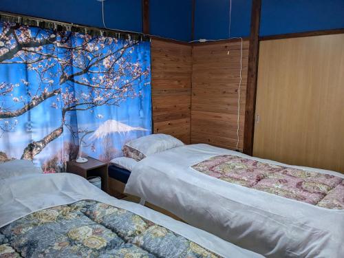 a bedroom with two beds and a tree mural at Guest house AIZU First in Aizuwakamatsu