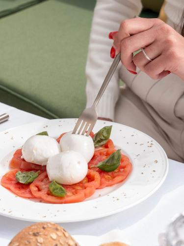a woman eating a plate of food with a fork at Villa Certosa in Capri