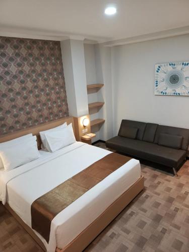 a bedroom with a large bed and a couch at Grand Plaza Boutique Hotel in Karawang