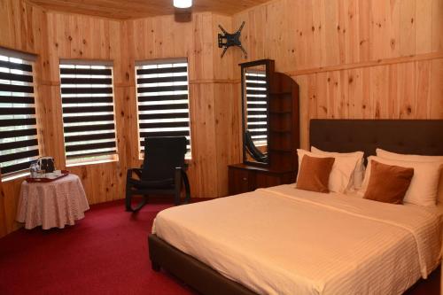 a bedroom with a bed and wooden walls and windows at The Fern Inn in Nuwara Eliya