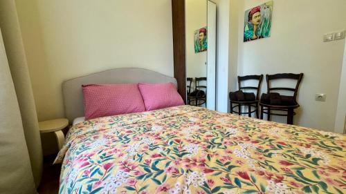 a bedroom with a bed with pink pillows and chairs at 2 Bedrooms Top Central Apartment on Vitosha Boulevard in Sofia