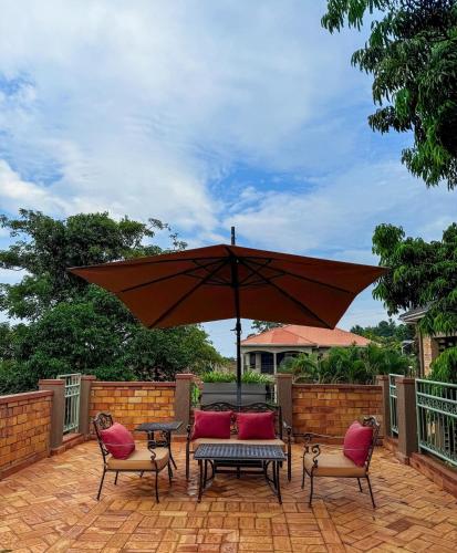 a patio with a table and chairs and an umbrella at Tooro Green Courts in Namulanda