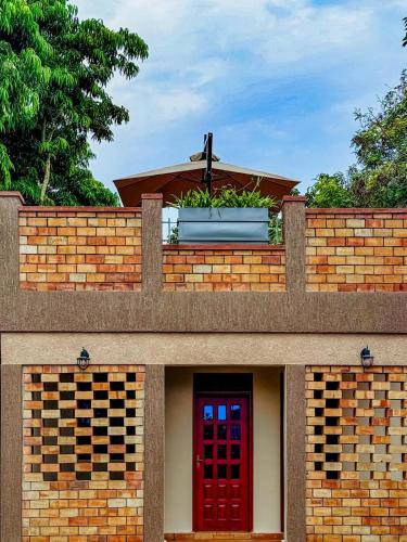 a red door in a brick wall with a cross on top at Tooro Green Courts in Namulanda