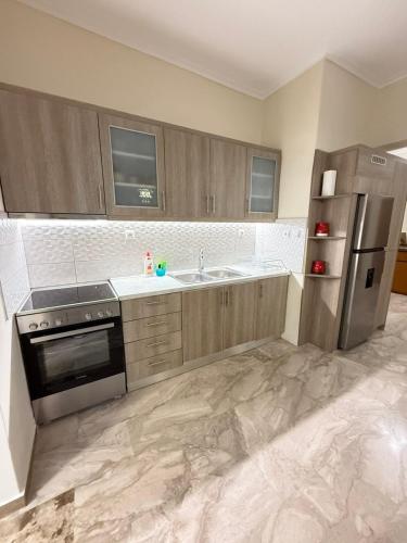 a kitchen with wooden cabinets and a stainless steel refrigerator at Efesou Large Apartment in Néa Éfesos