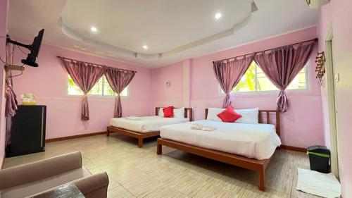 two beds in a room with pink walls and windows at Chai Patchara Resort in Ban Nong Ban Kao