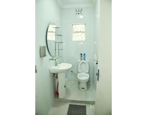 a white bathroom with a toilet and a sink at Spacious Town House in Nakuru in Nakuru