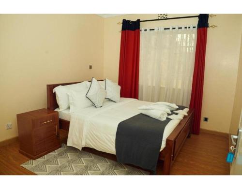 a bedroom with a bed with red curtains at Spacious Town House in Nakuru in Nakuru
