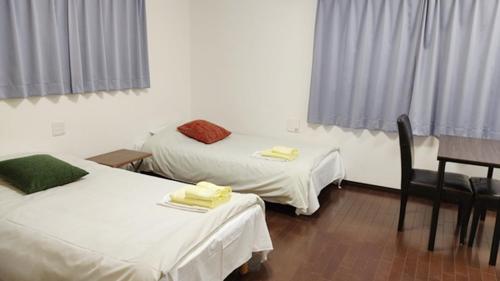a room with two beds and a table and chairs at Hotel Chuo Oasis in Osaka