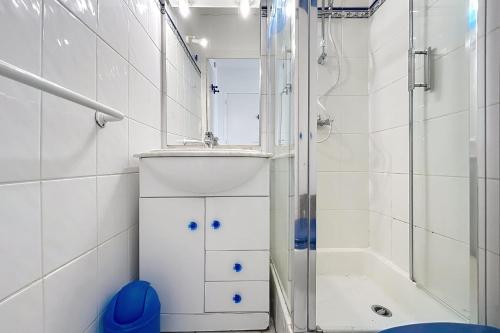 une salle de bain blanche avec une douche et un lavabo dans l'établissement Le Bleuet - Emplacement idéal - Face à la mer, à Fleury