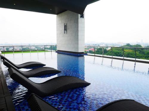 a swimming pool with black chairs in the water at Fairview House - Luxstay near Airport in Klapadua