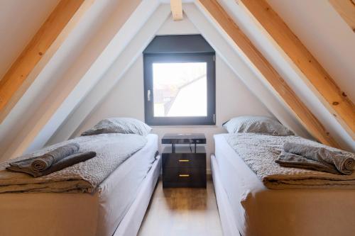 two beds in a attic room with a window at Brandneues Stadtglanz Apartment in Stuttgart