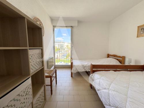 une petite chambre avec deux lits et une fenêtre dans l'établissement front de mer 2 chambres parking quartier corniche, à Sète