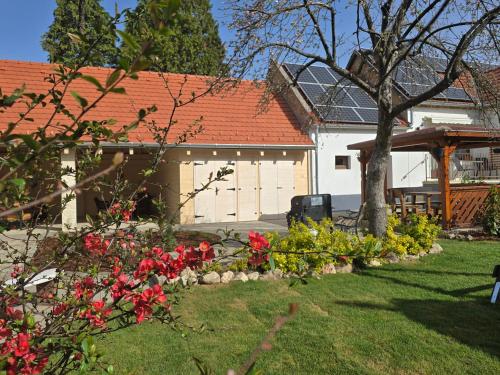 a house with a yard with flowers and a tree at Bakonyi Kiscsillag Bakonybél in Bakonybél