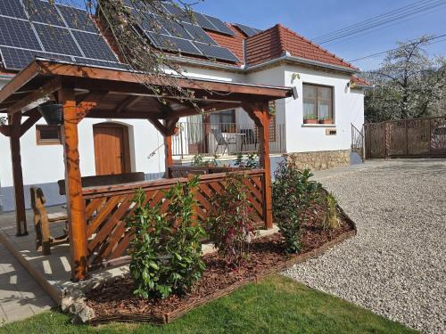 a wooden pergola in front of a house with solar panels at Bakonyi Kiscsillag Bakonybél in Bakonybél