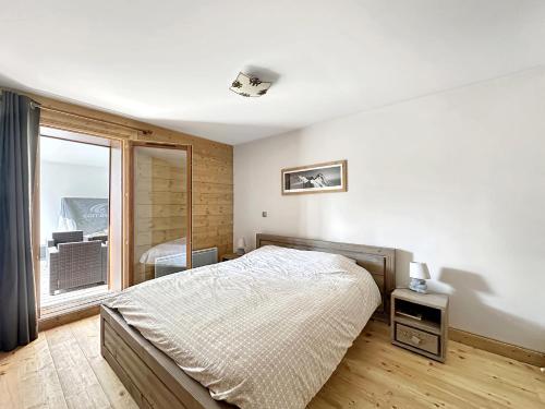 une chambre avec un lit et une grande fenêtre dans l'établissement ROUS02 Appartement 6 8 personnes au centre station, aux Carroz d'Arâches
