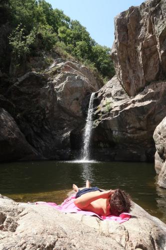 un homme se posant sur une couverture dans l'eau près d'une cascade dans l'établissement Petit coin de paradis, à Dunières-sur-Eyrieux