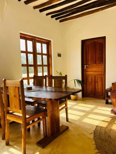 a dining room with a wooden table and chairs at Nyota ya Amani, Shela Lamu in Shela