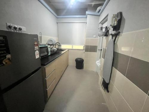 a small kitchen with a refrigerator and a stove at Z Residence Pangsapuri Ladang Tok Pelam in Kuala Terengganu