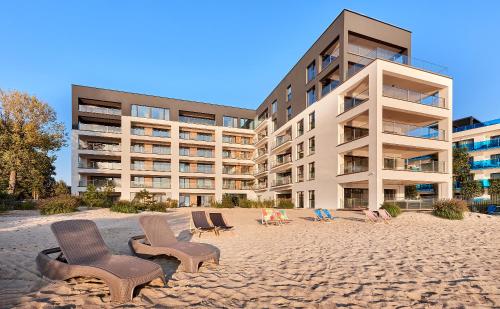 a sandy beach with chairs and a building at Boszkowo Horizon Park Apartament 21 "Lazurowy" in Boszkowo