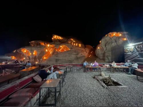 a group of people sitting at tables in front of a rock formation at wadi rum land mars in Wadi Rum