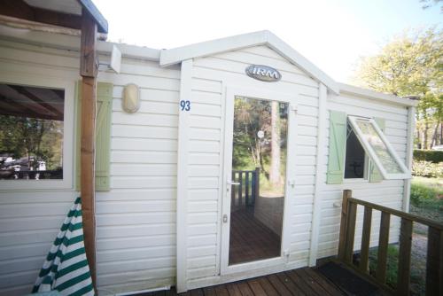 a door to a tiny house with a deck at Mobil-home Saint-Chéron 91530 Camping Parc des roches in Mirgaudon