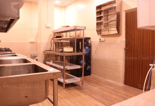 a kitchen with a sink and a shelf with a microwave at Woodlands Wilderness Chalet in Mādāri Hāt