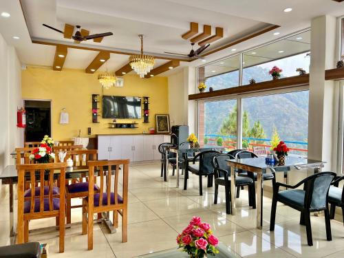 a dining room with tables and chairs and a large window at Dhurva Hotel and Resort in Naugaon