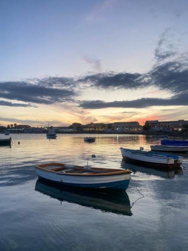 a group of boats sitting in the water at sunset at Appartamento Fronte Mare Marzamemi in Marzamemi