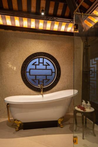 a bath tub in a bathroom with a sign on the wall at Ancient Huế Garden Houses in Hue