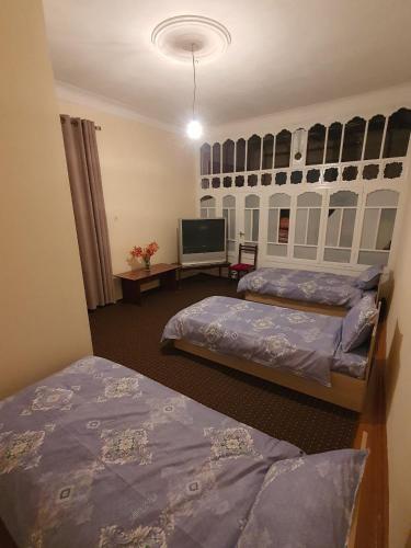 a room with two beds and a flat screen tv at Muslima Guest House in Muruntau
