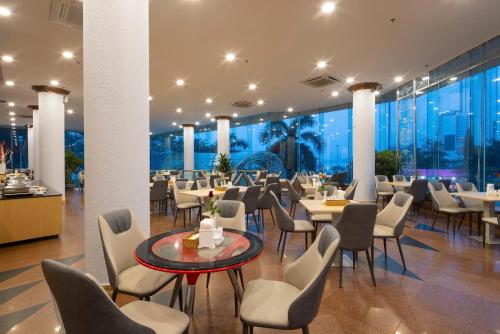 a restaurant with tables and chairs and windows at Nha Trang Lodge Hotel in Nha Trang