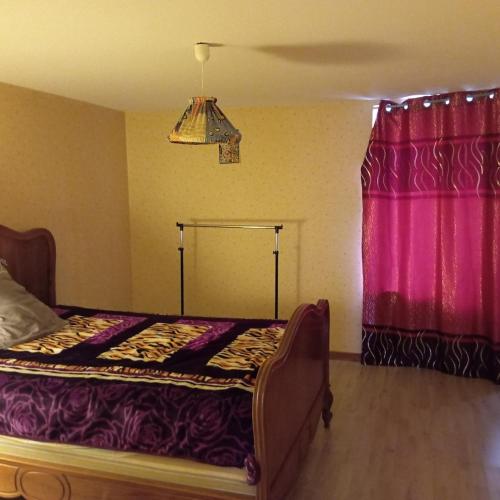 - une chambre avec un lit et un rideau rose dans l'établissement La vie en rose, à Courpière