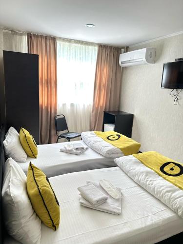 a hotel room with two beds with yellow pillows at Aura Plaza Hotel in Tbilisi City