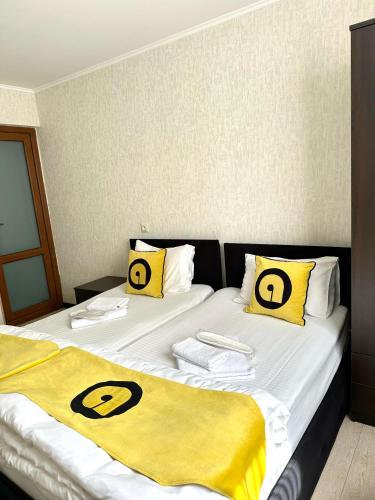 two beds in a room with yellow and black pillows at Aura Plaza Hotel in Tbilisi City
