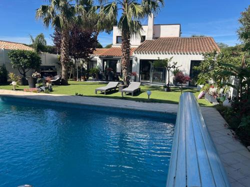 une piscine devant une maison avec des palmiers dans l'établissement LOCATION Vacances VILLA PISCINE JARDIN, à La Grande Motte
