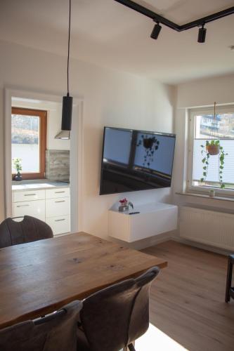 a dining room with a wooden table and a tv at Direkt am See Winterberg Elkeringhausen in Winterberg