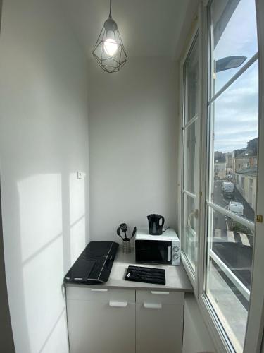 une cuisine blanche avec une cuisinière et une fenêtre dans l'établissement T2 - Cocon Coeur d'Angers - 4 personnes, à Angers