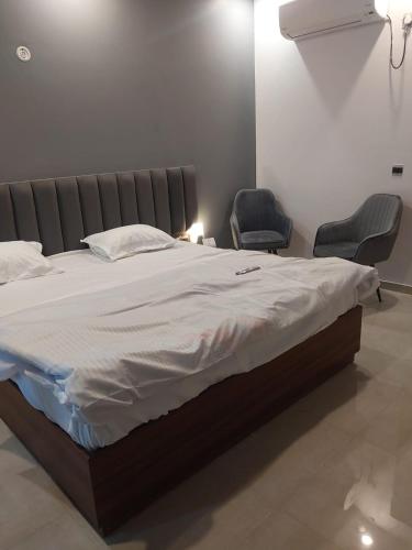a large bed with two chairs in a bedroom at Omaxe New Hazratganj in Nilmatha