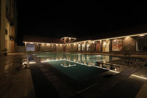 a swimming pool lit up at night with lights at Sarovar Portico, Somnath in Somnath