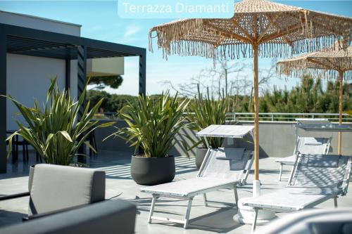 a patio with chairs and tables and umbrellas at Residence I Diamanti - Siroli Collection in Cervia