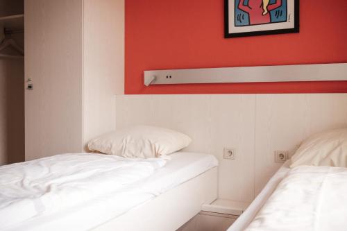two beds in a room with red and white walls at Jugendgästehaus Aasee in Münster