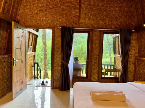 a bedroom with a bed and large glass windows at Azhani Bungalow in Tetebatu