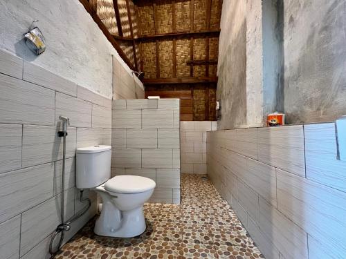 a bathroom with a white toilet in a room at Azhani Bungalow in Tetebatu